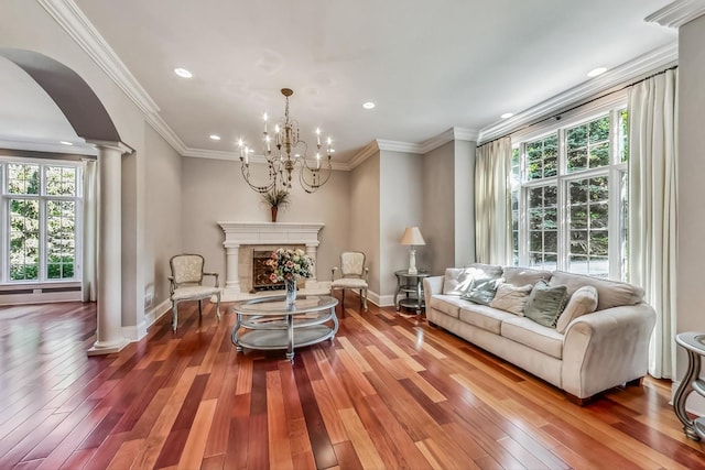 living room featuring ornamental molding, ornate columns, a chandelier, and wood-type flooring