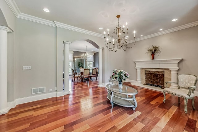 sitting room with ornate columns, crown molding, a chandelier, and wood-type flooring