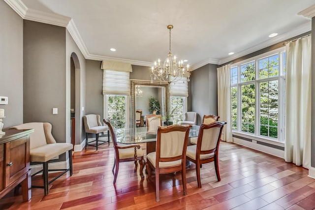 dining space featuring crown molding, a notable chandelier, hardwood / wood-style flooring, and a wealth of natural light