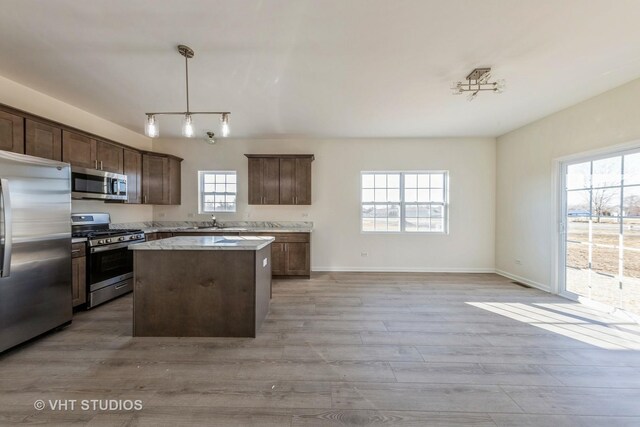 kitchen featuring a kitchen island, light hardwood / wood-style floors, appliances with stainless steel finishes, pendant lighting, and dark brown cabinetry