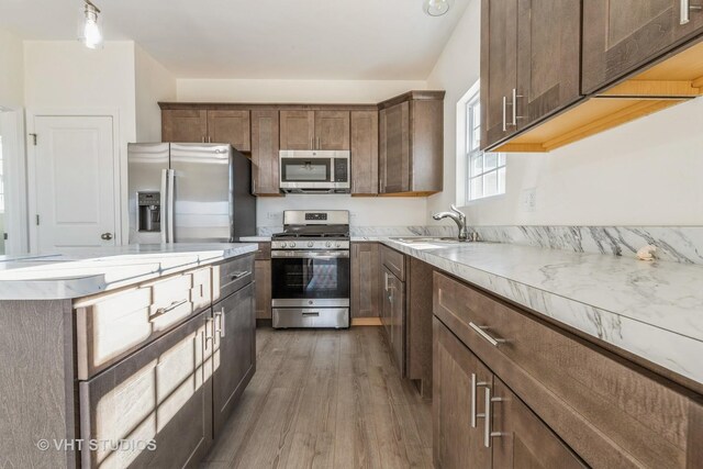 kitchen with dark brown cabinets, dark hardwood / wood-style flooring, stainless steel appliances, decorative light fixtures, and sink