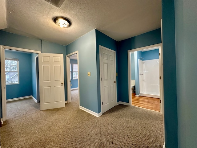 unfurnished bedroom featuring ensuite bath, a textured ceiling, and light hardwood / wood-style flooring