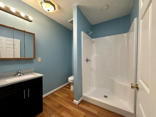 bathroom featuring a shower, hardwood / wood-style floors, toilet, and vanity