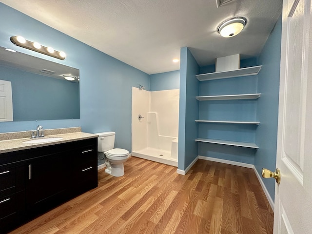 bathroom featuring vanity, a shower, hardwood / wood-style floors, and toilet