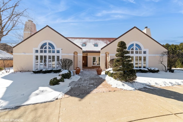 mediterranean / spanish-style home with french doors, a chimney, and stucco siding