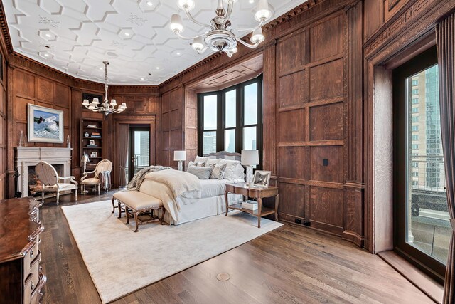 159 E Walton Pl Unit Ph, Chicago, IL 60611 - bedroom with a chandelier, wooden walls, crown molding, a fireplace, and light wood-style floors