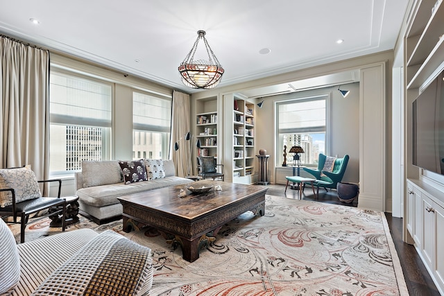 living room featuring ornamental molding, built in shelves, and hardwood / wood-style floors