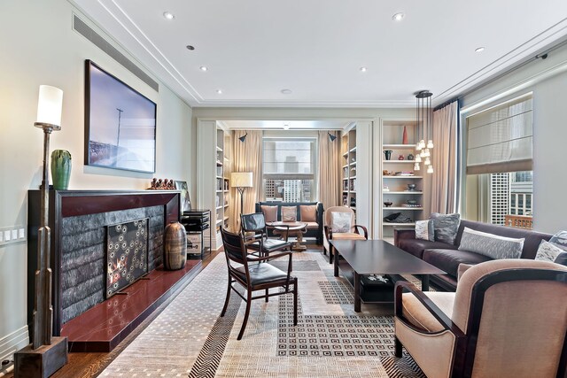 living room featuring built in features, crown molding, recessed lighting, a high end fireplace, and wood finished floors