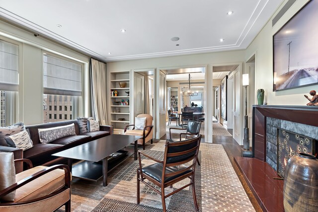 living room with built in features, a fireplace, recessed lighting, an inviting chandelier, and wood finished floors