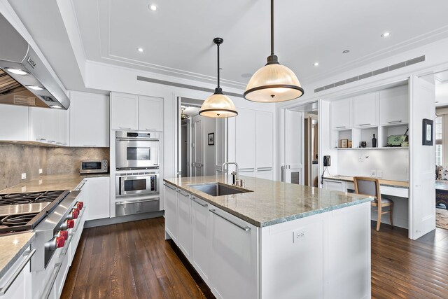 kitchen with dark wood-style floors, appliances with stainless steel finishes, ventilation hood, a sink, and a warming drawer