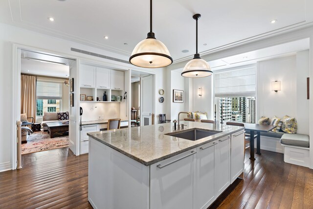 kitchen with dark wood finished floors, light stone counters, a sink, and white cabinetry