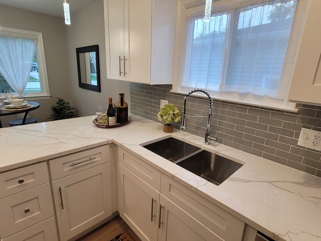 kitchen with sink, white cabinets, tasteful backsplash, and light stone counters