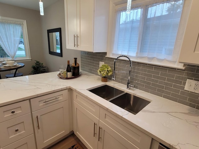 kitchen with white cabinetry, light stone countertops, and sink