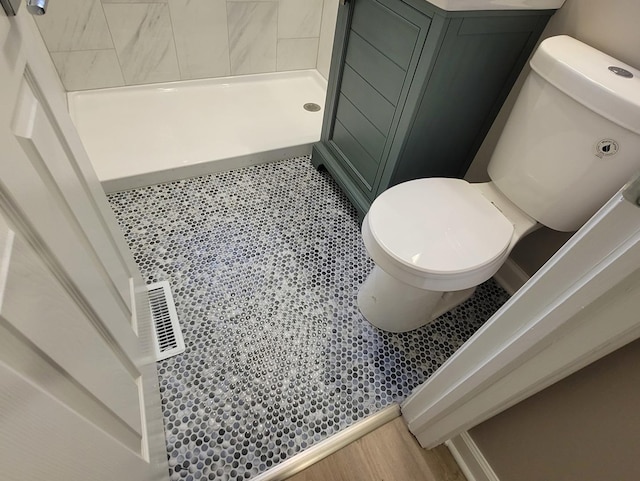 bathroom with a tile shower and toilet