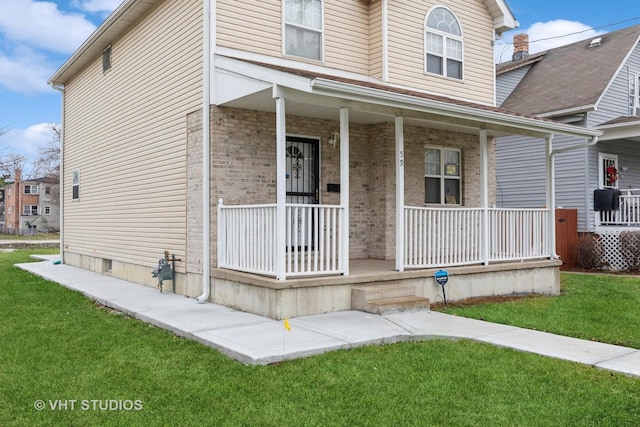 view of front facade featuring brick siding, a porch, and a front yard