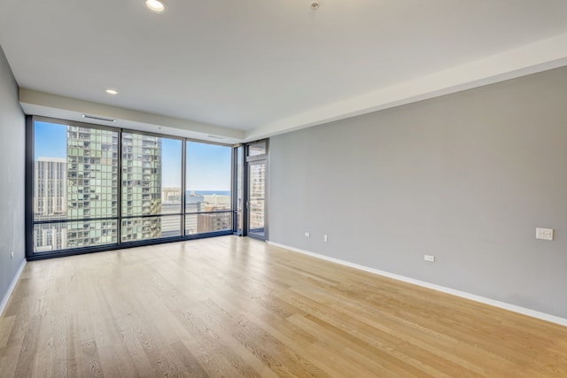 unfurnished room featuring a wall of windows and light hardwood / wood-style flooring