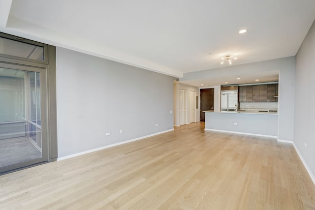 unfurnished living room with light hardwood / wood-style flooring and sink