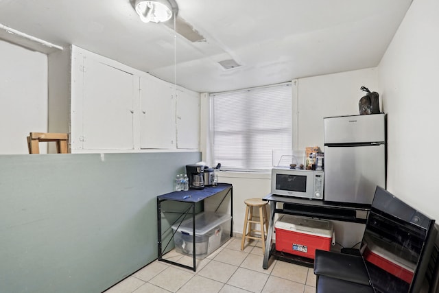 kitchen with white cabinets, stainless steel refrigerator, and light tile patterned floors