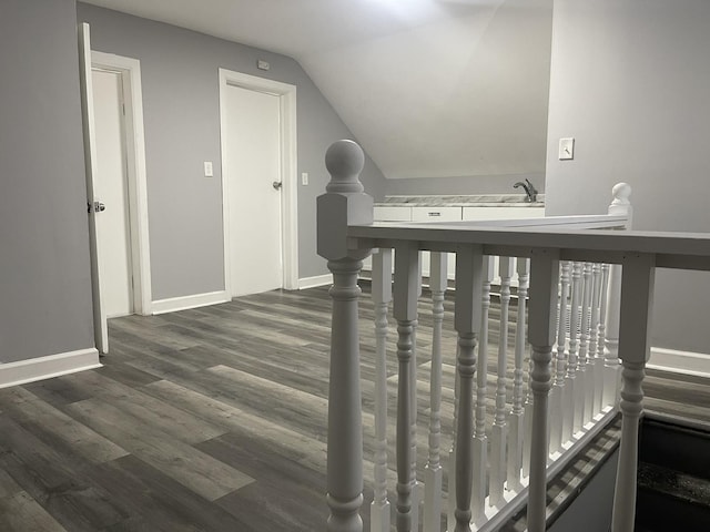 hallway with dark wood-type flooring and vaulted ceiling