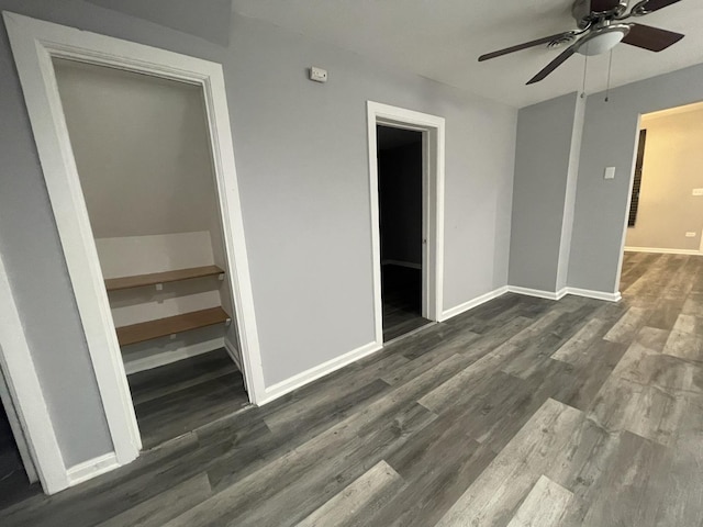 unfurnished bedroom with ceiling fan, a closet, a spacious closet, and dark hardwood / wood-style floors