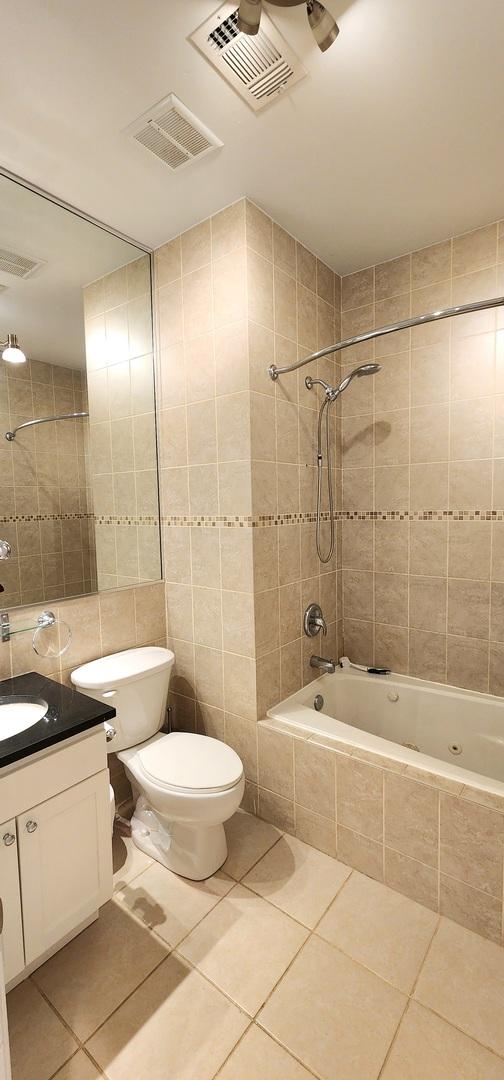 full bathroom featuring tile patterned floors, vanity, tiled shower / bath combo, and tile walls