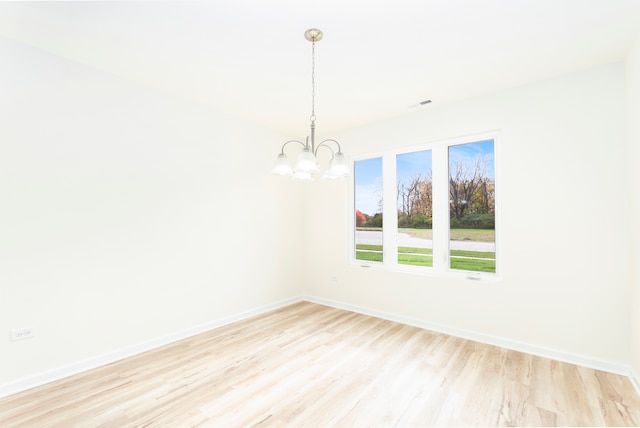 unfurnished room featuring an inviting chandelier and light wood-type flooring