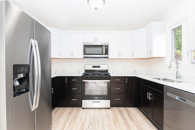 kitchen with sink, appliances with stainless steel finishes, light hardwood / wood-style flooring, and white cabinetry