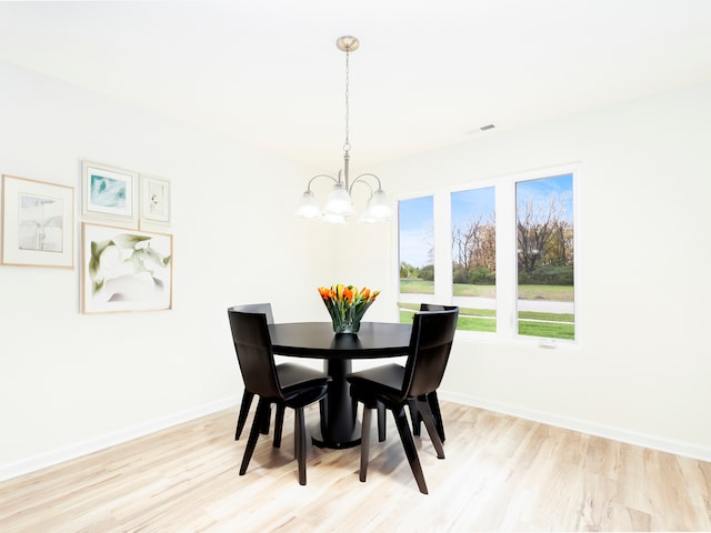 dining space with light hardwood / wood-style flooring and an inviting chandelier