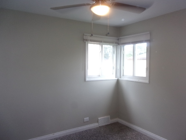 unfurnished room with ceiling fan and carpet