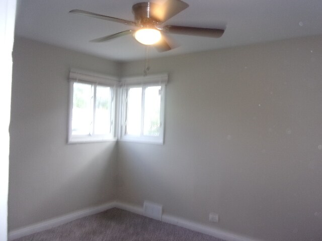 empty room featuring carpet flooring and ceiling fan