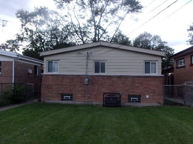 back of house with a lawn and central AC