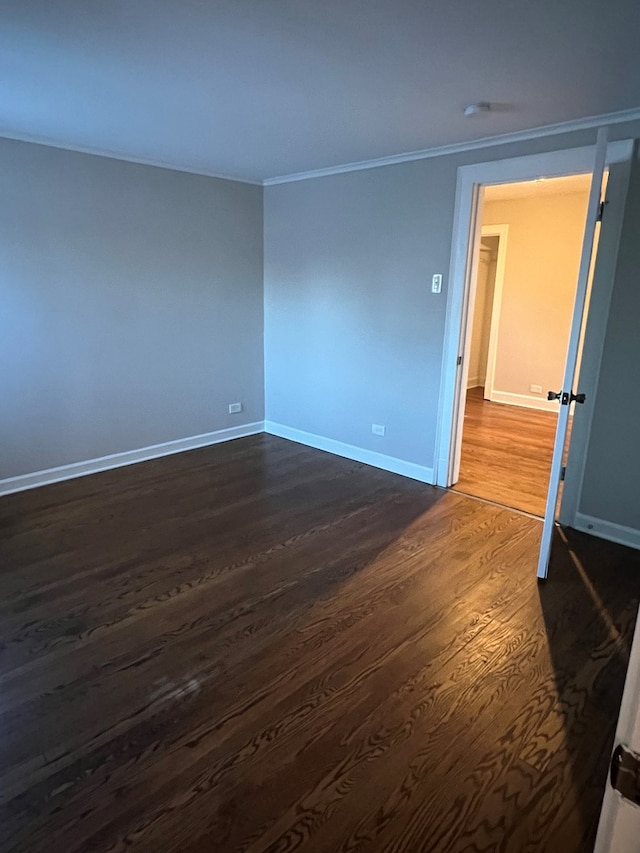 empty room featuring crown molding and dark wood-type flooring