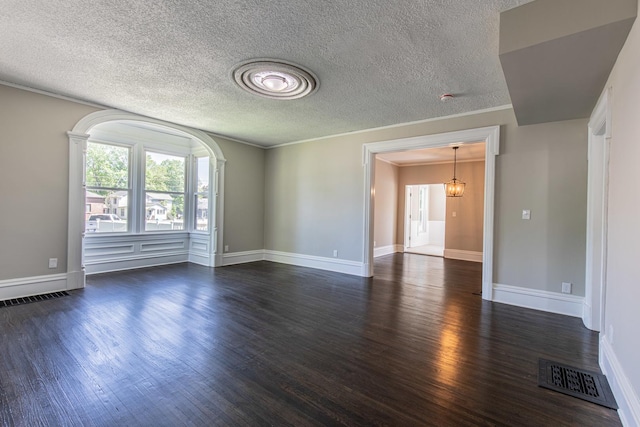 1011 5th St, Mendota, IL 61342 - empty room featuring dark wood-style flooring, a chandelier, baseboards, a textured ceiling, and arched walkways