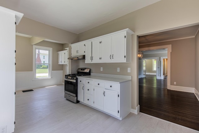 1011 5th St, Mendota, IL 61342 - kitchen featuring stainless steel range with gas stovetop, under cabinet range hood, light wood finished floors, light countertops, and white cabinetry