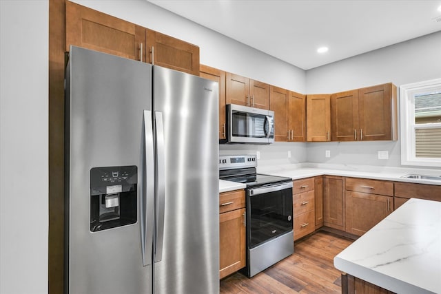 kitchen featuring light stone countertops, appliances with stainless steel finishes, and hardwood / wood-style floors