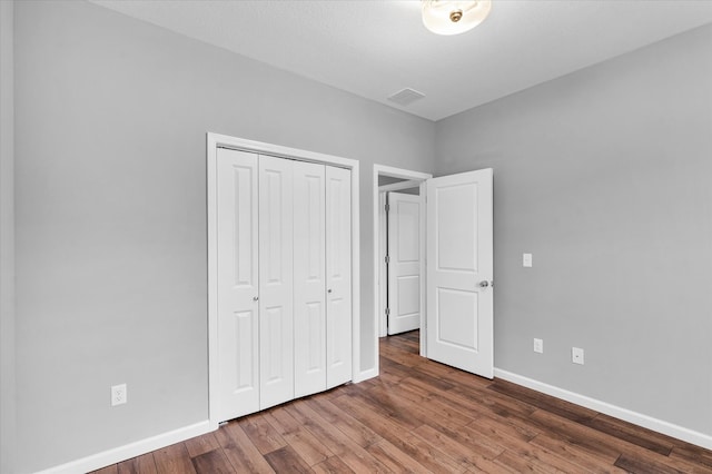 unfurnished bedroom featuring a closet, dark hardwood / wood-style flooring, and a textured ceiling