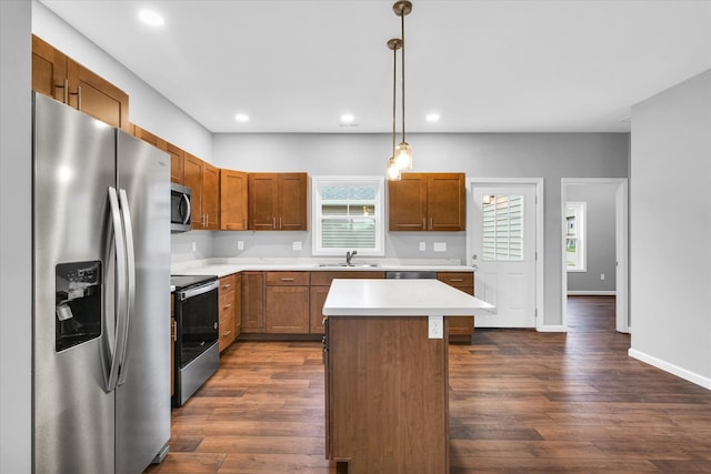 kitchen featuring a center island, dark wood-type flooring, sink, appliances with stainless steel finishes, and decorative light fixtures