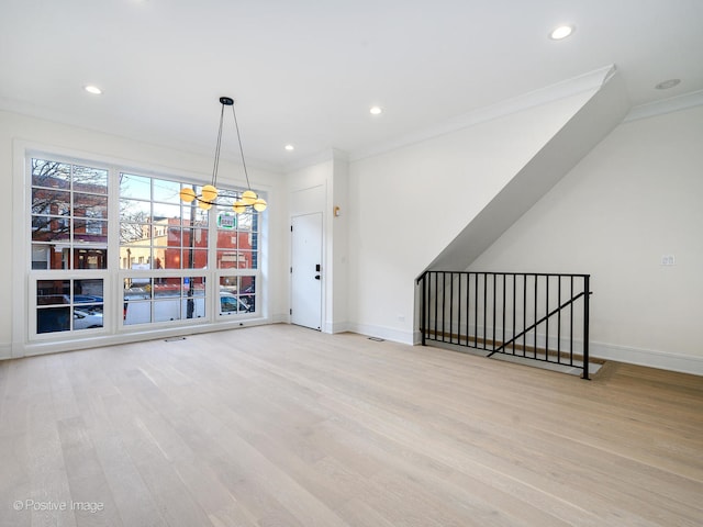 interior space featuring an inviting chandelier, ornamental molding, and light hardwood / wood-style flooring