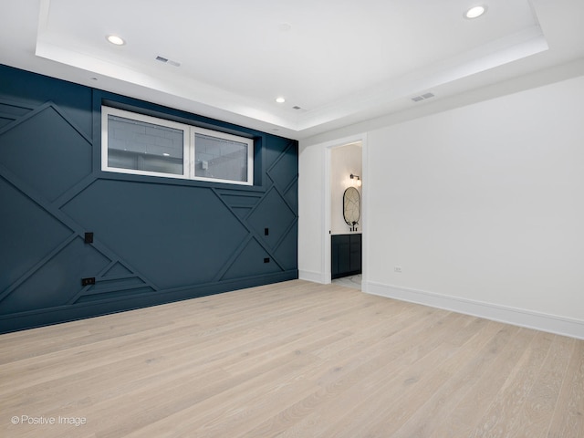 spare room featuring a raised ceiling and light wood-type flooring