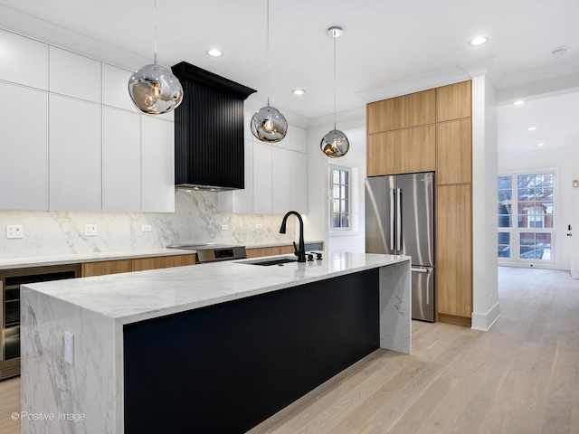 kitchen with stainless steel refrigerator, decorative light fixtures, sink, light hardwood / wood-style flooring, and white cabinets