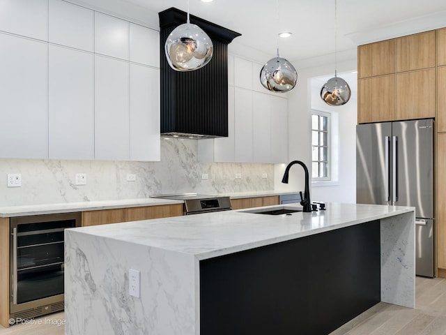 kitchen with white cabinets, wine cooler, a center island with sink, and light hardwood / wood-style flooring