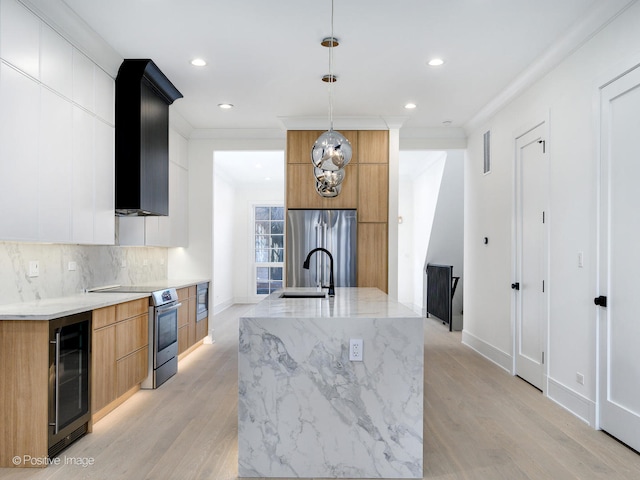 kitchen featuring appliances with stainless steel finishes, pendant lighting, beverage cooler, and light hardwood / wood-style floors