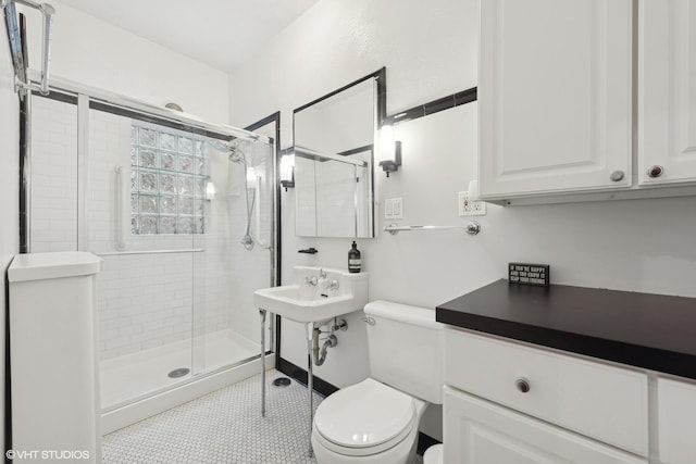 bathroom with an enclosed shower, sink, and toilet