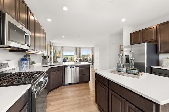 kitchen featuring dark brown cabinets, stainless steel appliances, and light wood-type flooring