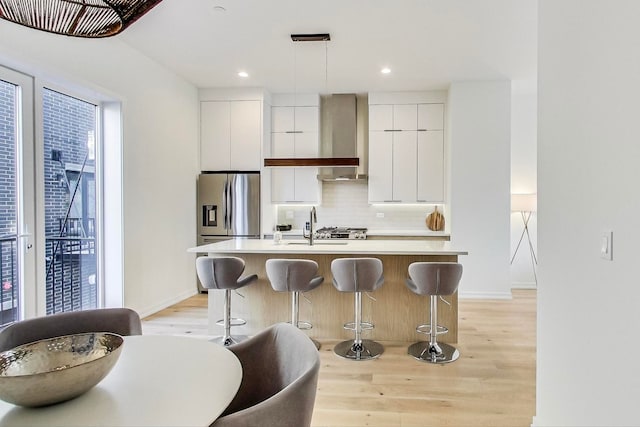 kitchen with a kitchen island with sink, stainless steel refrigerator with ice dispenser, and light wood-type flooring