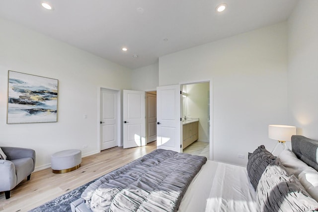 bedroom with ensuite bath and light wood-type flooring