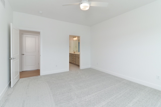 unfurnished bedroom featuring ceiling fan, ensuite bathroom, and light carpet