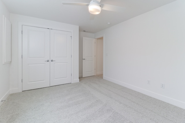 unfurnished bedroom featuring light colored carpet, a closet, and ceiling fan