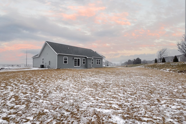 snow covered back of property featuring central air condition unit