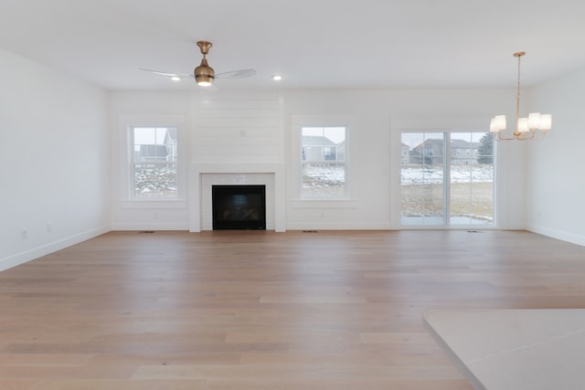 unfurnished living room with light hardwood / wood-style floors and ceiling fan with notable chandelier